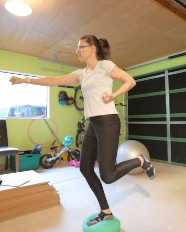 woman (emma) exercising on a bosun ball, punching the air.