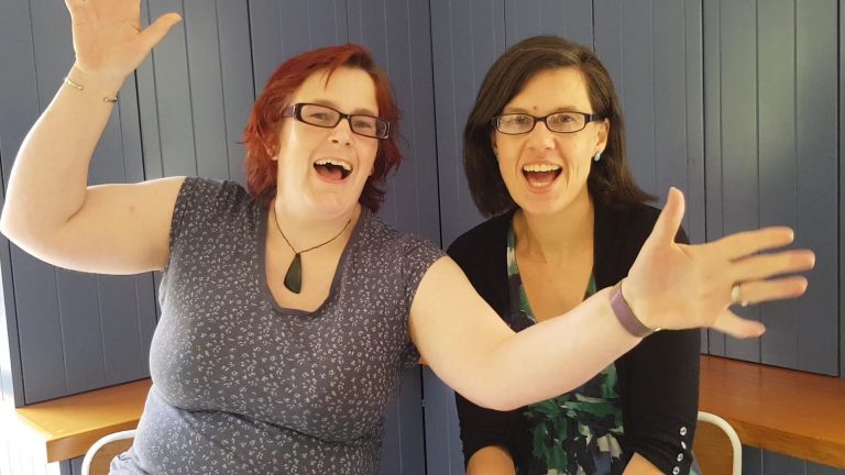kitty and emma both laughing into a camera.