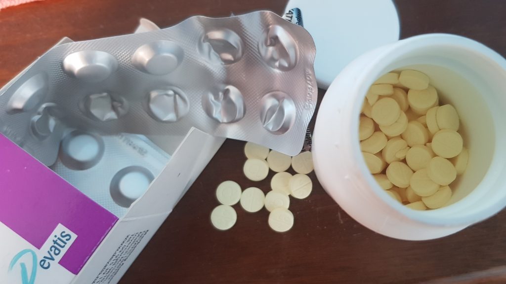 blister pack of tablets and a pill bottle containing yellow round pills.